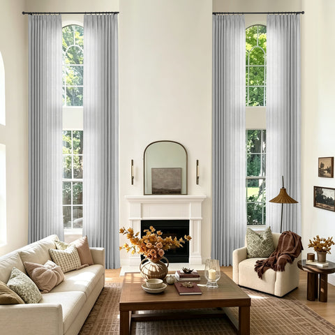 A styled living room with two tall window treatments featuring light gray sheer curtains