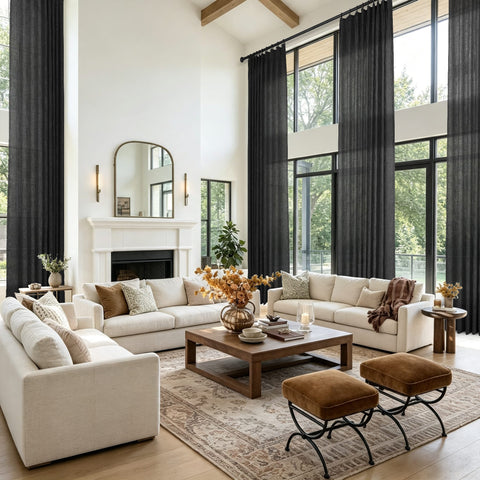 A bright modern living room featuring a cream sectional sofa and tall black window curtains