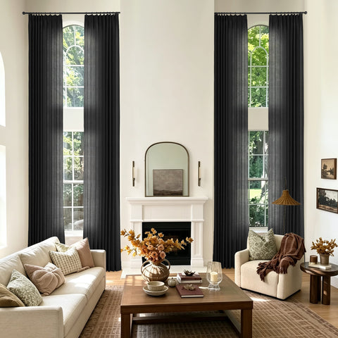 A styled living room with two tall black curtain panels hanging on either side of large arched windows