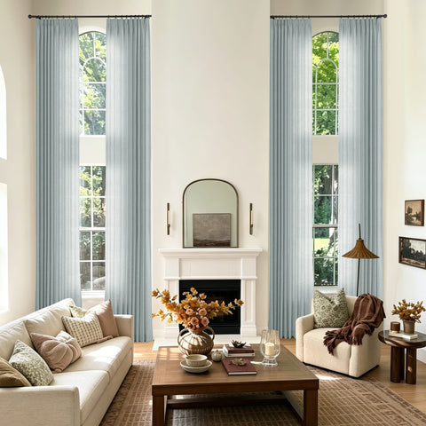 A styled living room with tall light blue curtains hanging on both sides of two large arched windows